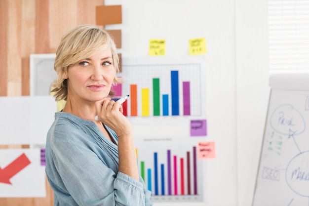 Femme d&#39;affaires réfléchie écrit sur un tableau blanc