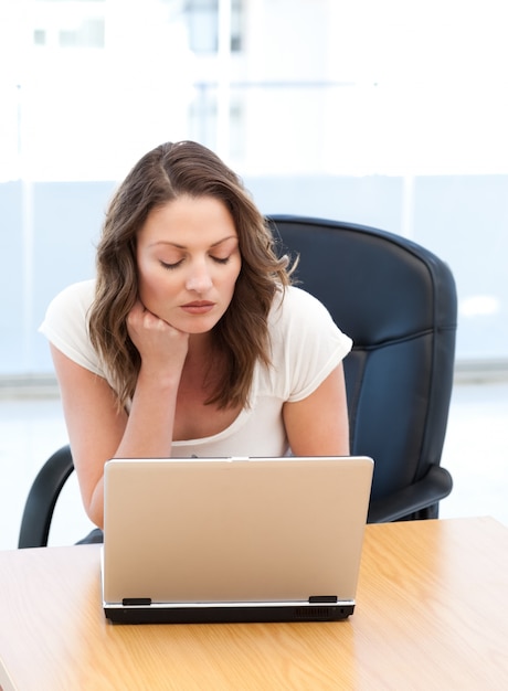 Femme d&#39;affaires réfléchie travaillant sur un ordinateur portable à une table