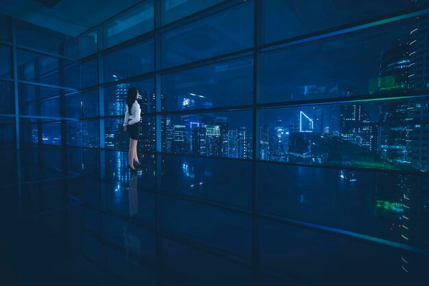 Une femme d'affaires regardant une belle ville la nuit.