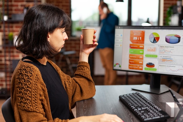 Femme d'affaires regardant un écran d'ordinateur analysant des graphiques de gestion travaillant à la stratégie marketing dans un bureau de démarrage. Directeur exécutif planifiant une réunion d'affaires à la recherche d'une solution d'entreprise