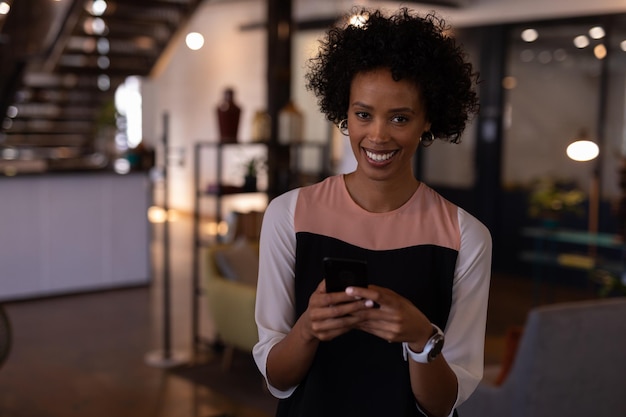 Photo une femme d'affaires regarde la caméra tout en utilisant un téléphone portable dans un bureau moderne