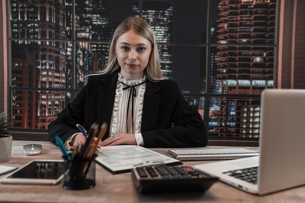 Une femme d'affaires remplit les formulaires fiscaux 1040 avec un ordinateur portable et une calculatrice au bureau