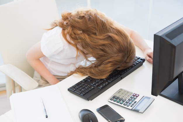 Femme d&#39;affaires reposant la tête sur le clavier au bureau