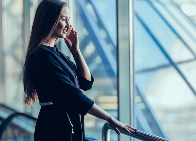 Femme d'affaires réussie avec un smartphone, debout devant o