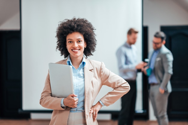 Femme d&#39;affaires réussie tenant un ordinateur portable et souriant.