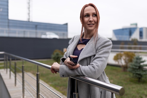 Femme d'affaires rousse d'affaires avec un téléphone portable dans des ses mains dans la perspective d'un