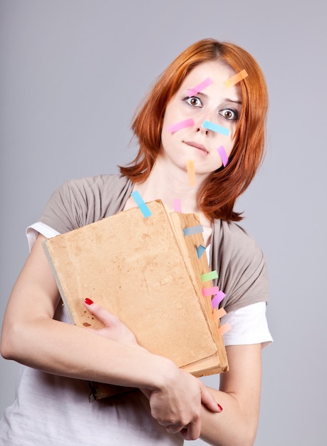 Femme d'affaires rousse avec livre et notes sur le visage.