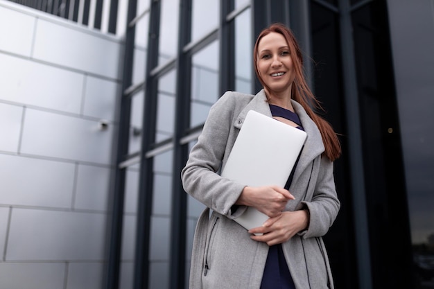 La femme d'affaires rousse va travailler avec un ordinateur portable