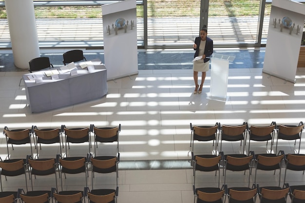 Photo une femme d'affaires s'entraîne à prononcer un discours dans une salle de conférence vide.