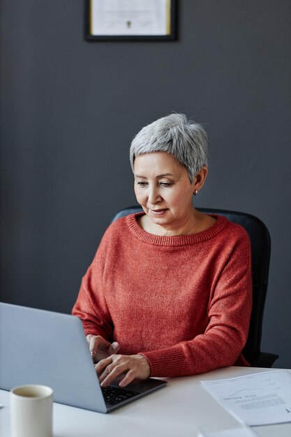 Femme d'affaires senior utilisant un ordinateur portable sur le lieu de travail au bureau