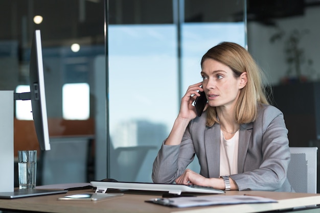 Femme d'affaires sérieuse et anxieuse parlant au téléphone travaillant dans un bureau moderne à l'ordinateur photo gros plan d'une conversation d'affaires