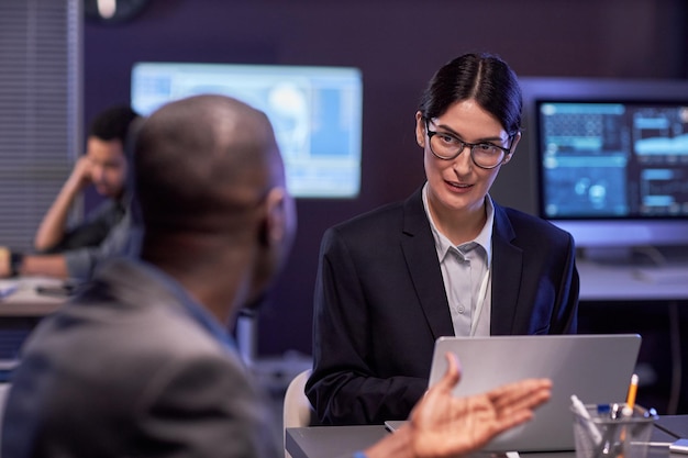 Femme d'affaires sérieuse utilisant un ordinateur portable lors d'une réunion au bureau informatique