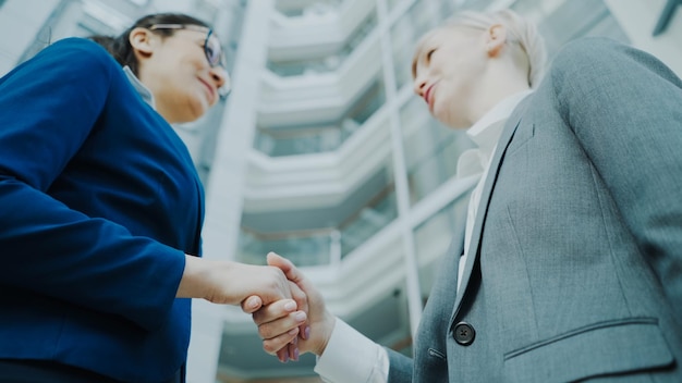 femme d'affaires serrant la main d'une collègue de travail dans le hall d'un immeuble de bureaux moderne