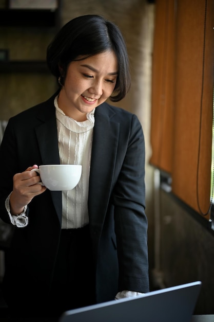 Une femme d'affaires en sirotant un café dans son bureau moderne