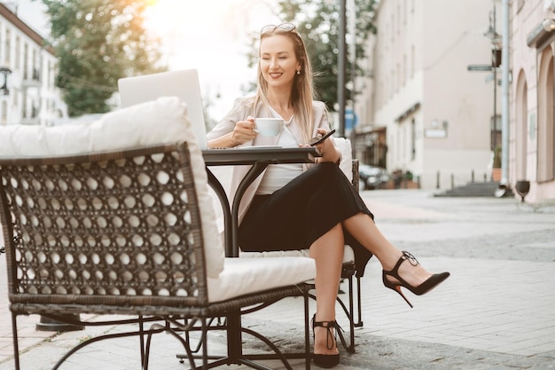 Femme d'affaires avec un smartphone assis à une table dans un café en plein air