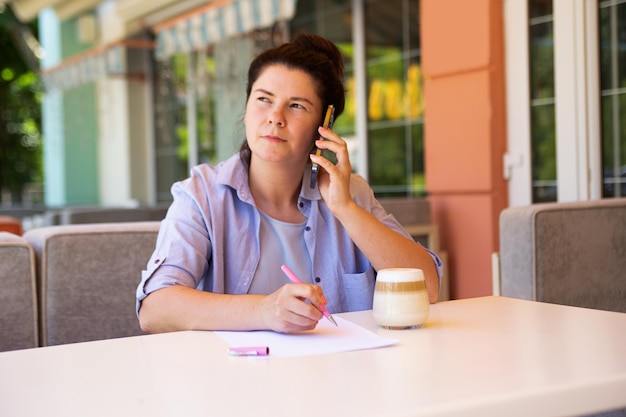 Femme d'affaires avec smartphone et tasse de café document signé à l'extérieur