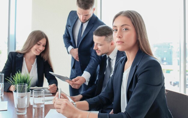 Femme d'affaires avec son groupe de personnes du personnel en arrière-plan au bureau lumineux moderne à l'intérieur