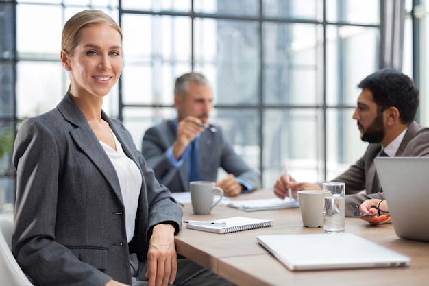 Femme d'affaires avec son groupe de personnes du personnel en arrière-plan au bureau lumineux moderne à l'intérieur