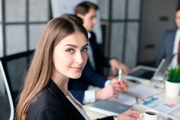 Femme d'affaires avec son personnel, groupe de personnes en arrière-plan dans un bureau moderne et lumineux à l'intérieur.