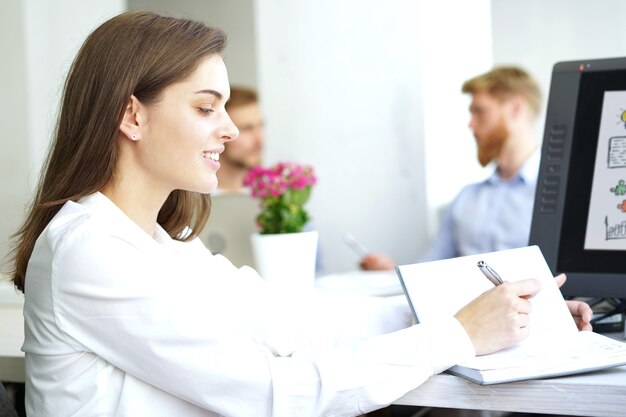 Femme d'affaires avec son personnel, groupe de personnes en arrière-plan dans un bureau moderne et lumineux à l'intérieur