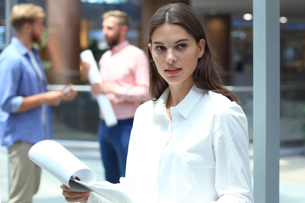 Femme d'affaires avec son personnel, groupe de personnes en arrière-plan dans un bureau moderne et lumineux à l'intérieur