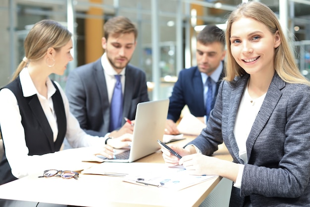 Femme d'affaires avec son personnel, groupe de personnes en arrière-plan dans un bureau moderne et lumineux à l'intérieur.