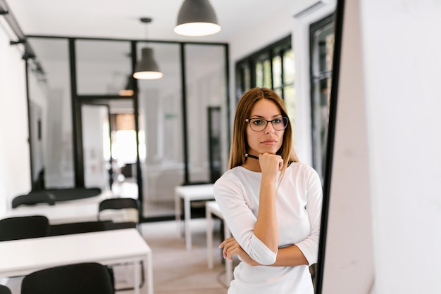 Femme d&#39;affaires songeur en regardant tableau blanc.