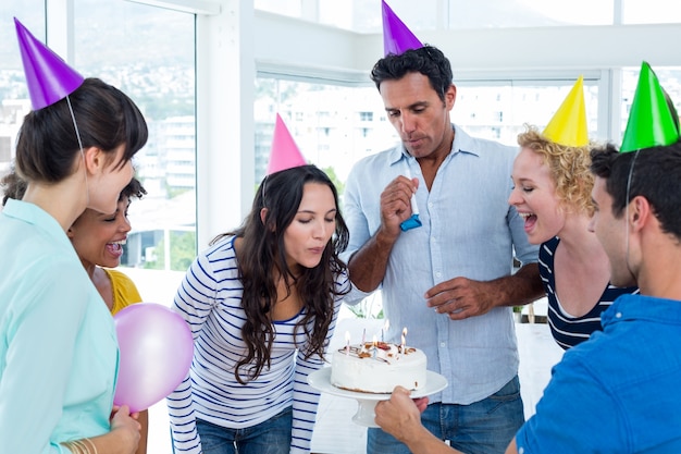 Femme d&#39;affaires soufflant des bougies sur son gâteau d&#39;anniversaire