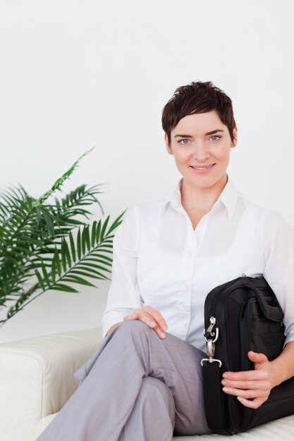 Femme d&#39;affaires souriant aux cheveux courts, assis sur un canapé