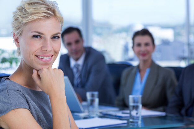 Femme d&#39;affaires, souriant à la caméra avec des collègues derrière