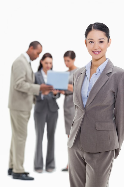 Femme d&#39;affaires souriant avec des collègues de travail en regardant un ordinateur portable en arrière-plan