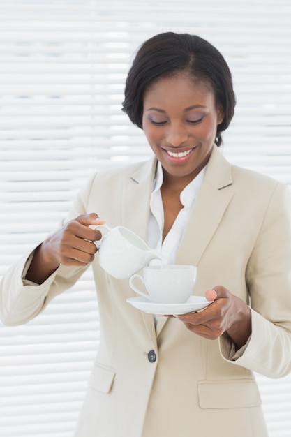 Femme d&#39;affaires souriant élégant avec une tasse de thé au bureau