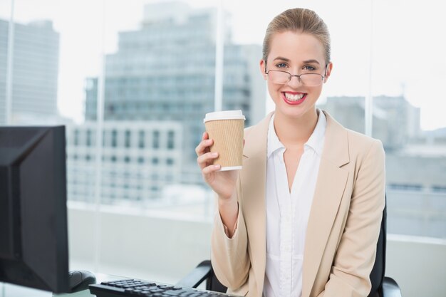 Femme d&#39;affaires souriant avec des lunettes, tenant le café