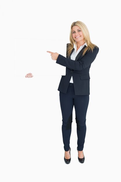 Femme d&#39;affaires souriant montrant un panneau blanc