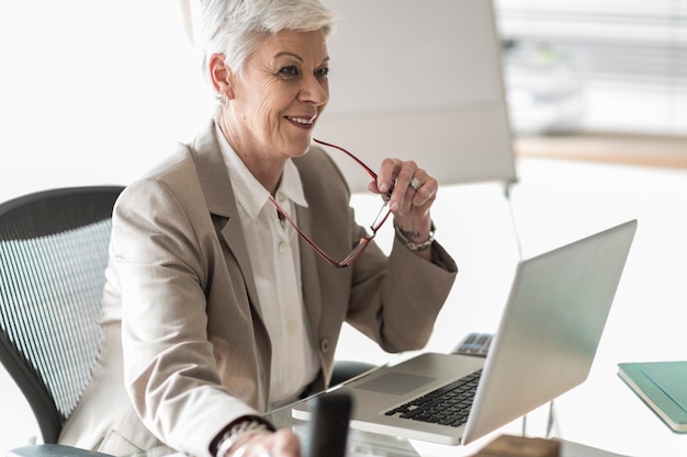 Photo femme d'affaires souriant avec ordinateur portable au bureau