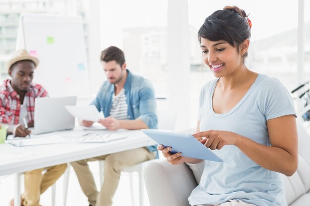 Femme d&#39;affaires souriant avec tablette sur canapé