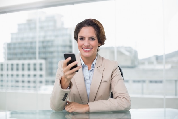 Femme d&#39;affaires en souriant et en tenant son smartphone