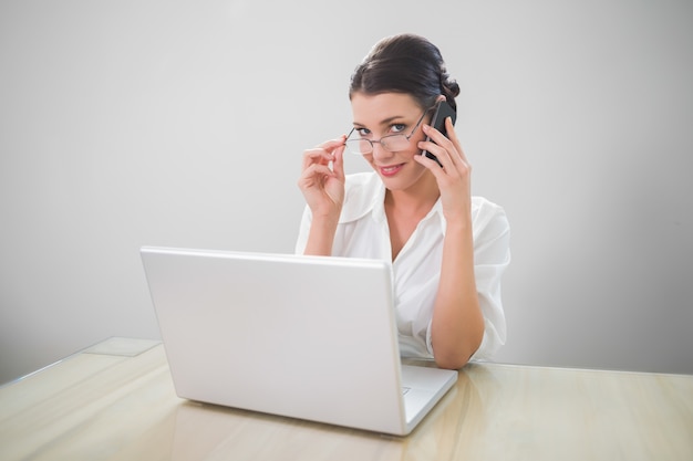 Femme d&#39;affaires souriant avec des verres chics téléphonant