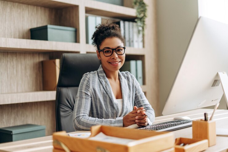 Photo une femme d'affaires souriante assise à un bureau travaillant sur un ordinateur dans un bureau moderne