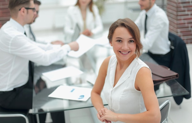 Femme d'affaires souriante assise devant le bureau, le concept de travail d'équipe