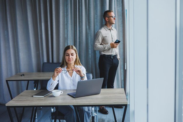 Femme d'affaires souriante assise à une table avec un ordinateur portable la gardant dos à son partenaire assis au bureau Le concept de travail d'équipe réussi