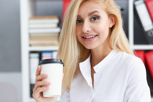 Femme d'affaires souriante, boire du café dans une tasse en papier