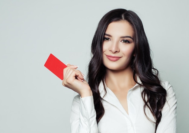 Femme d'affaires souriante avec carte vierge rouge Jeune femme tenant une carte vide dans ses mains Publicité commerciale marketing et concept de placement de produit