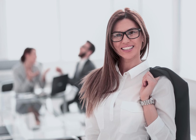 Femme d'affaires souriante debout avec une veste sur l'épaule