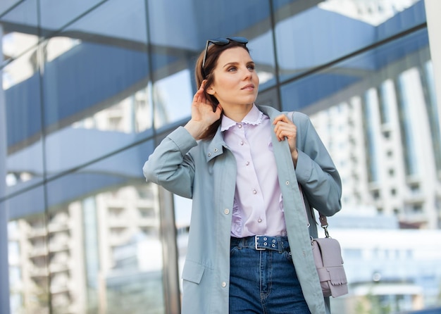 Femme d'affaires souriante et joyeuse dans une tente avec sac et lunettes de soleil boit du café sur le fond du centre d'affaires windows