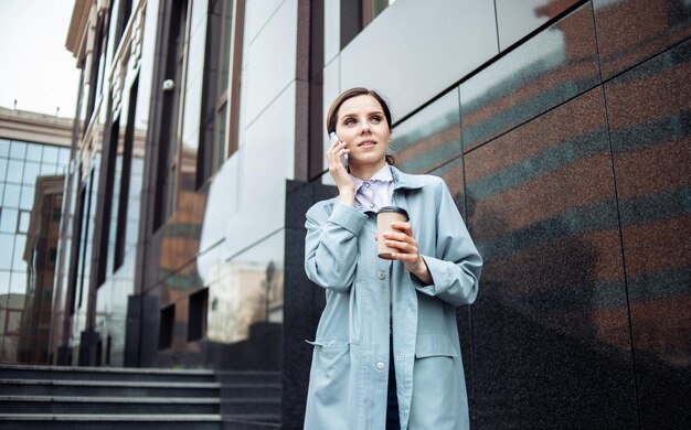 Femme d'affaires souriante moderne parlant au téléphone et buvant du café dans les escaliers Concept d'entreprise de style de vie