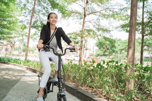 Femme d'affaires souriante, monté sur son vélo pliant