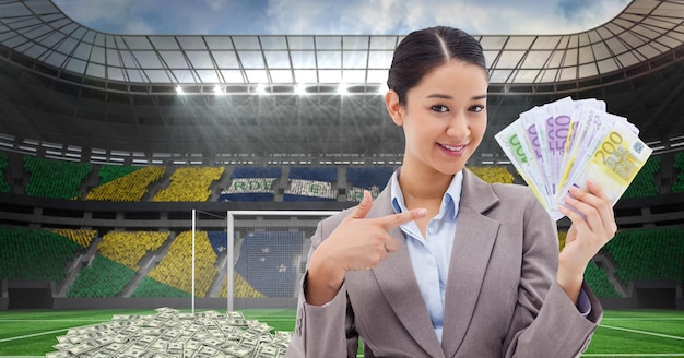 Femme d'affaires souriante montrant de l'argent au stade représentant la corruption