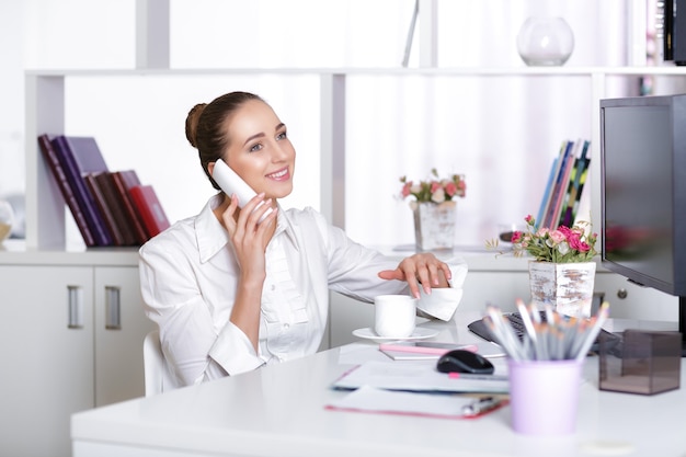 Femme d'affaires souriante parlant au téléphone au bureau.