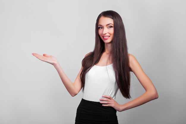 Femme d'affaires souriante pointant vers le haut et regardant l'avant sur un mur gris